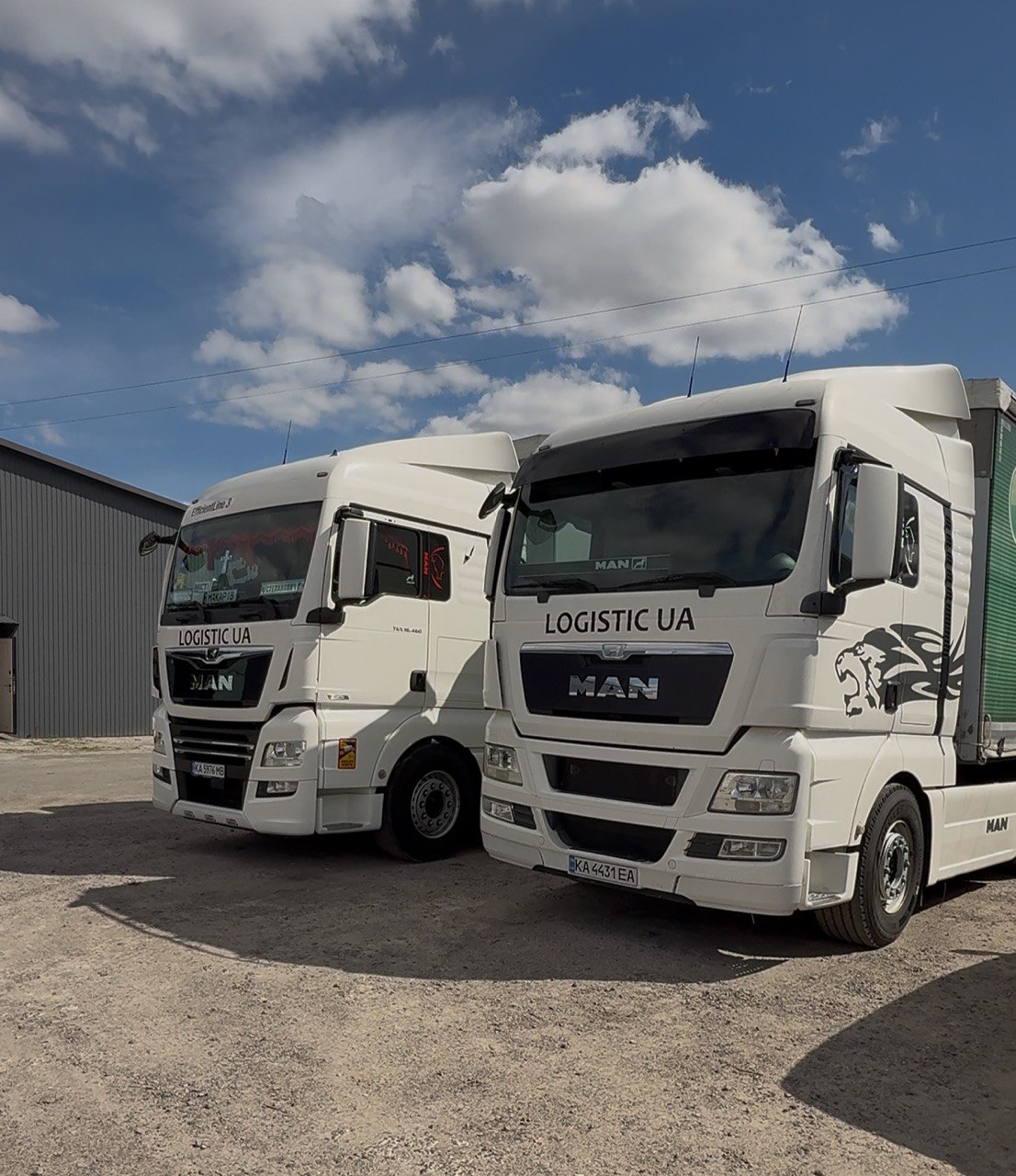Two LOGISTIC UA white MAN trucks parked side by side
